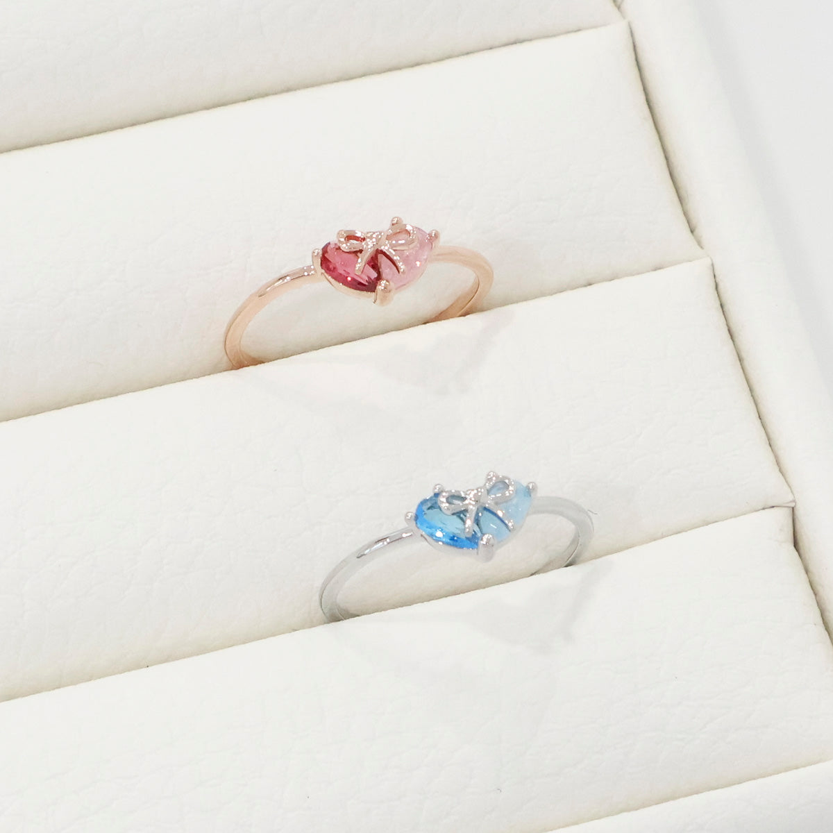 Two rings with gemstones on a white surface