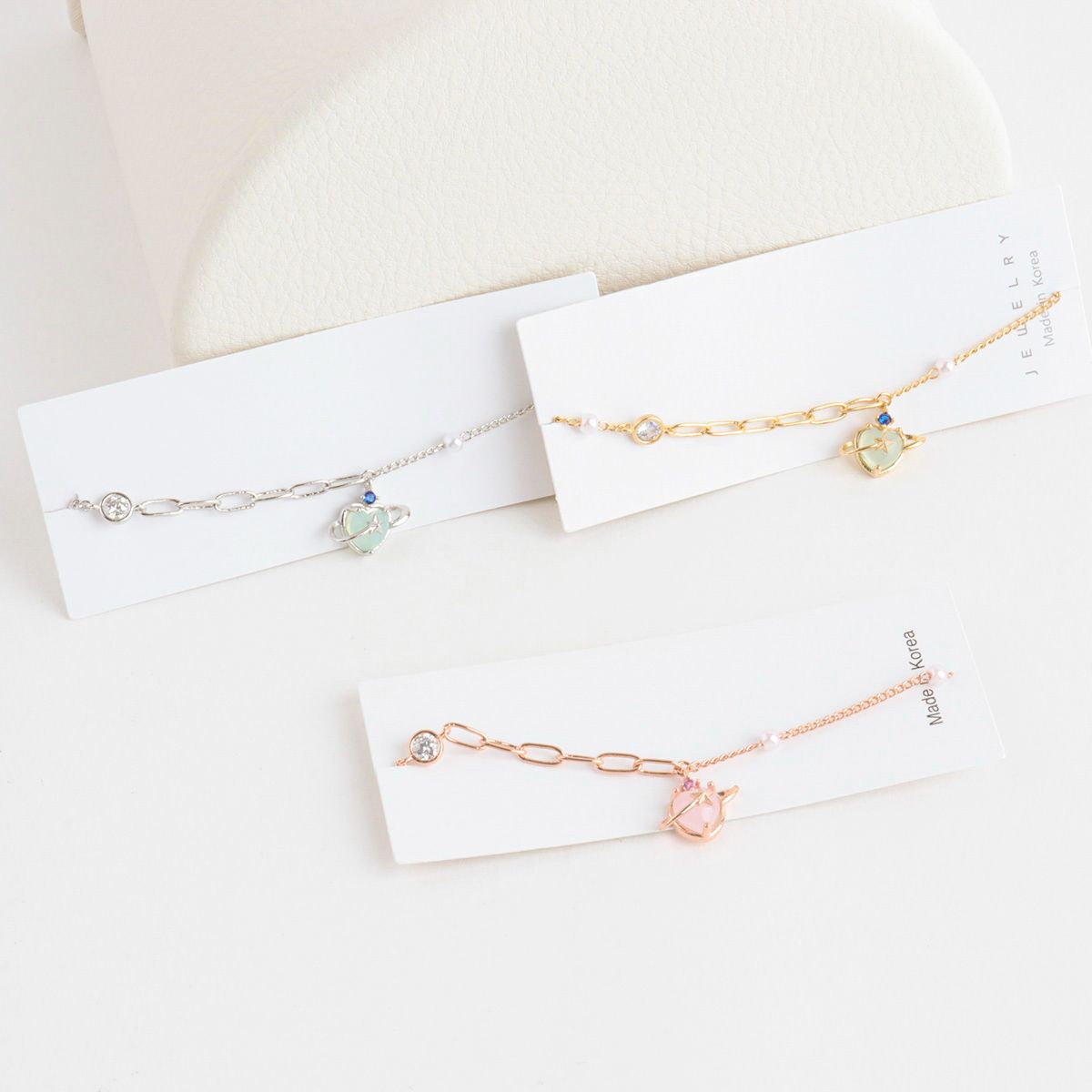 Three gold bracelets on white card holders with a soft beige background