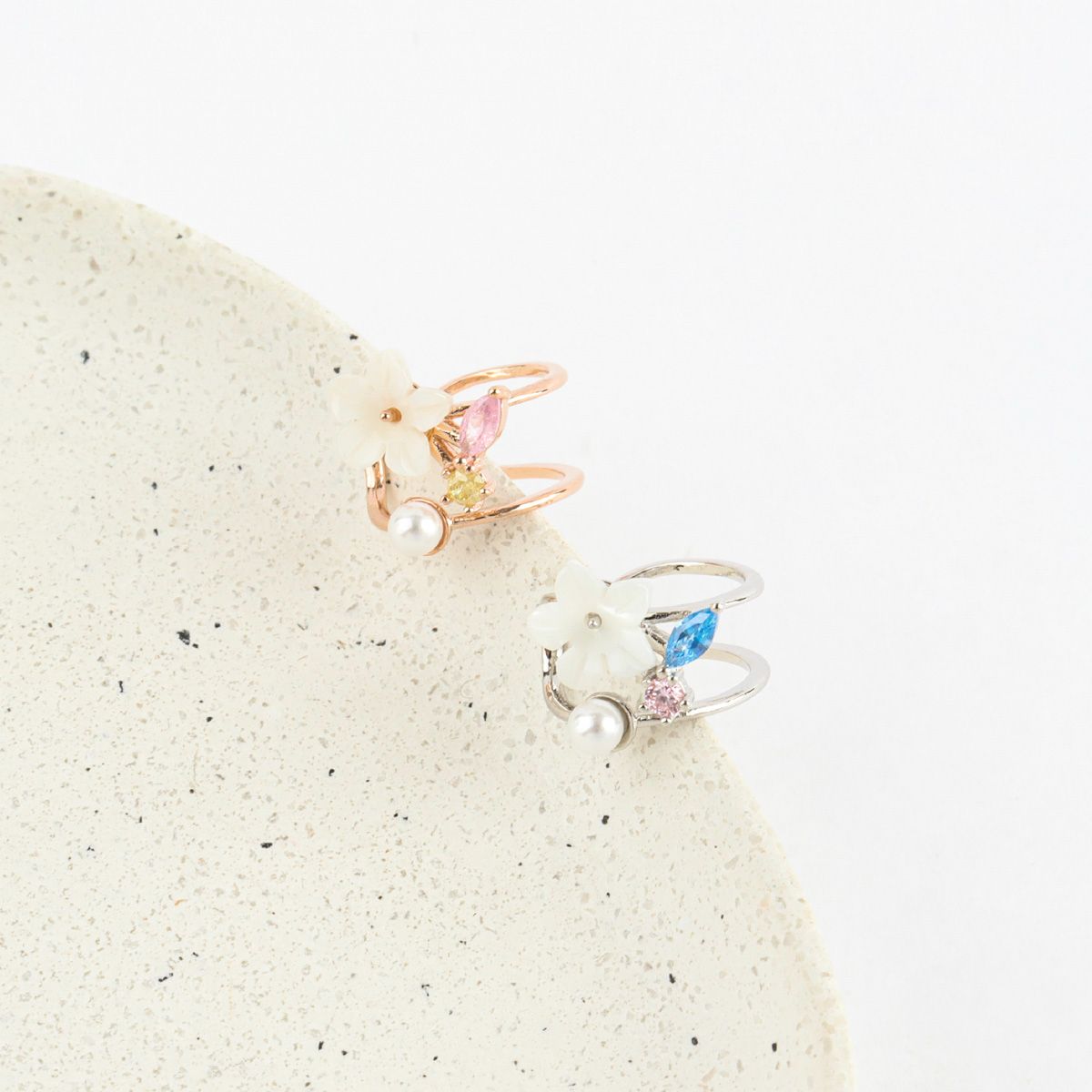 Two decorative rings with gemstones on a textured beige surface