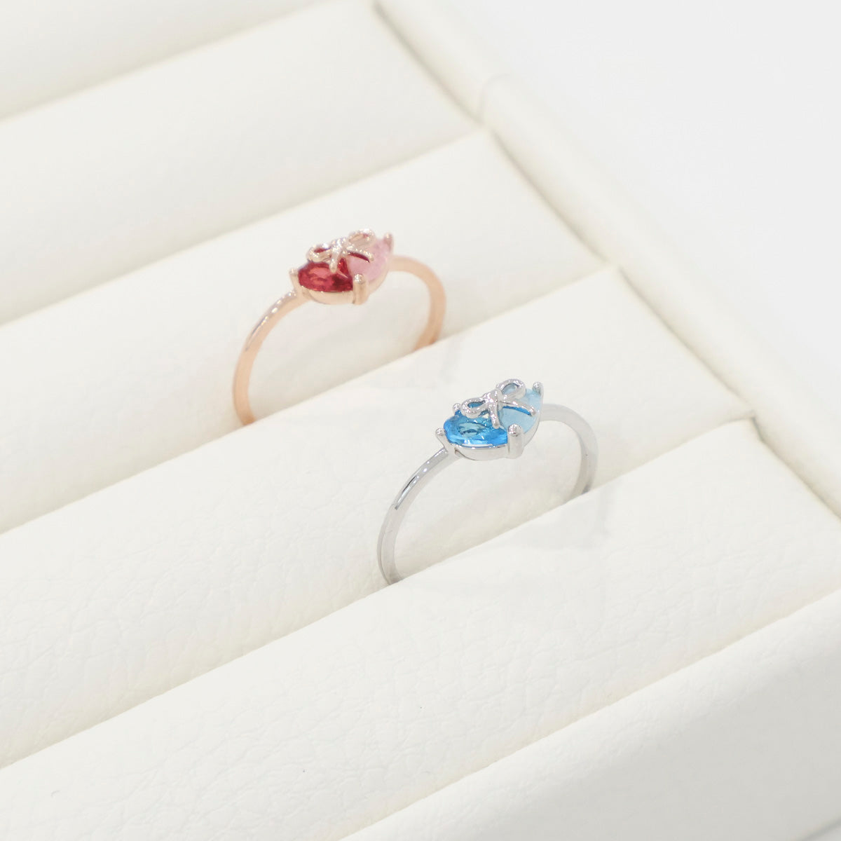 Two rings with heart-shaped gemstones on a white surface