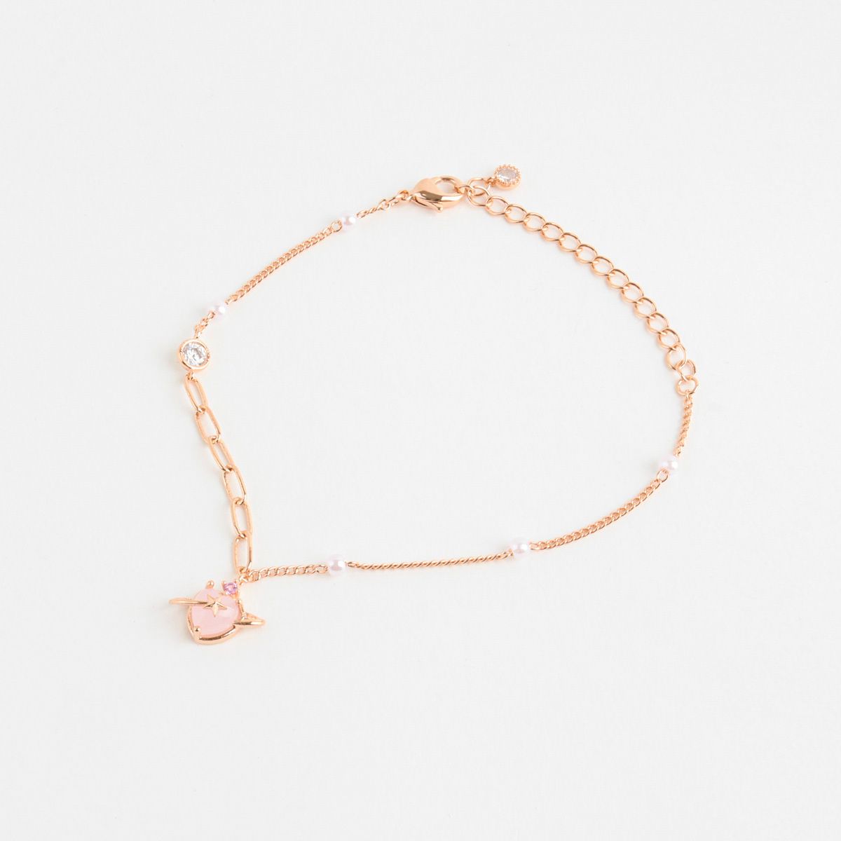 Rose gold bracelet with a heart charm on a light gray background