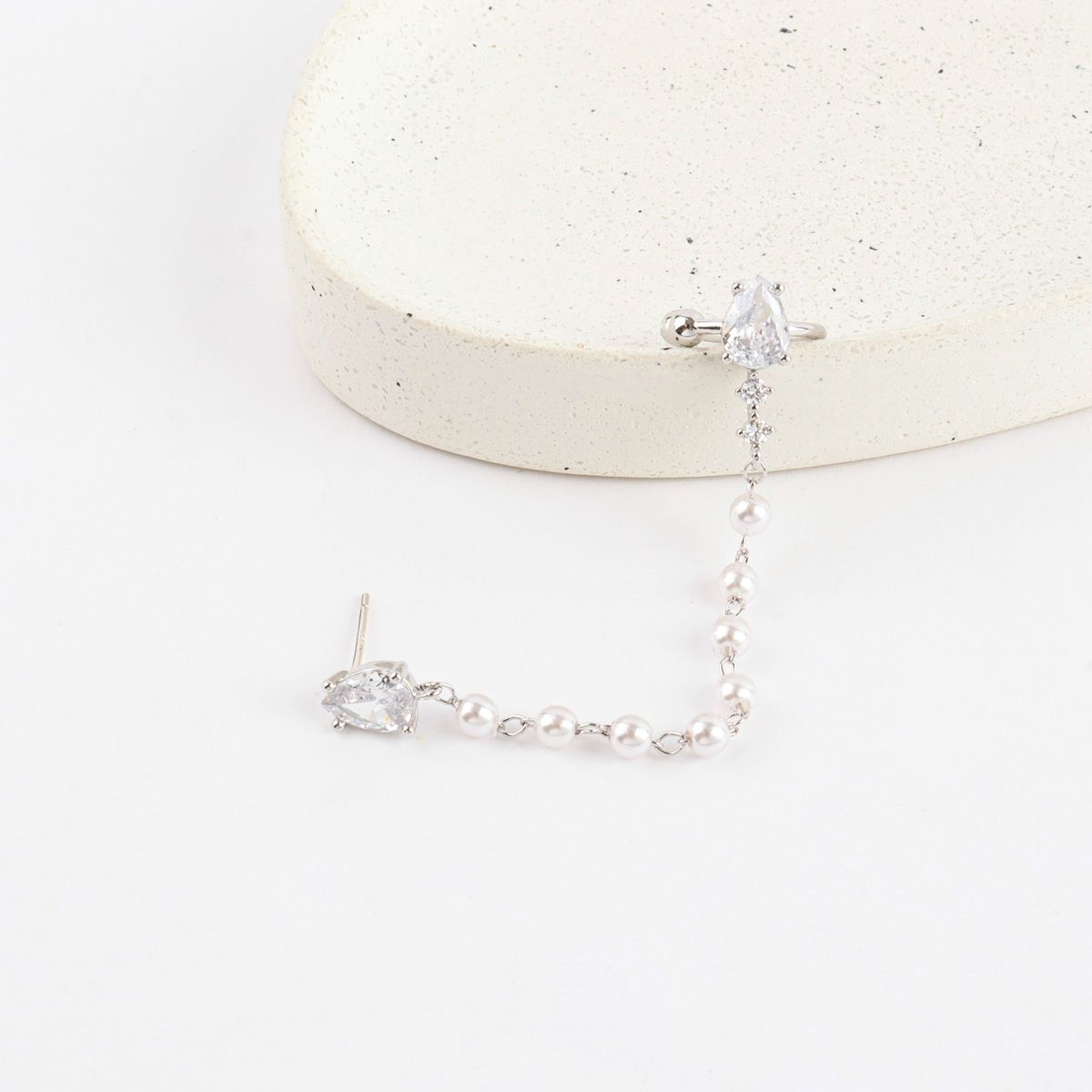 Silver earrings with clear gemstones on a white background