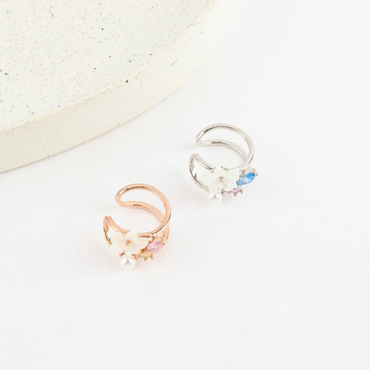 Two earcuffs with floral designs on a light background