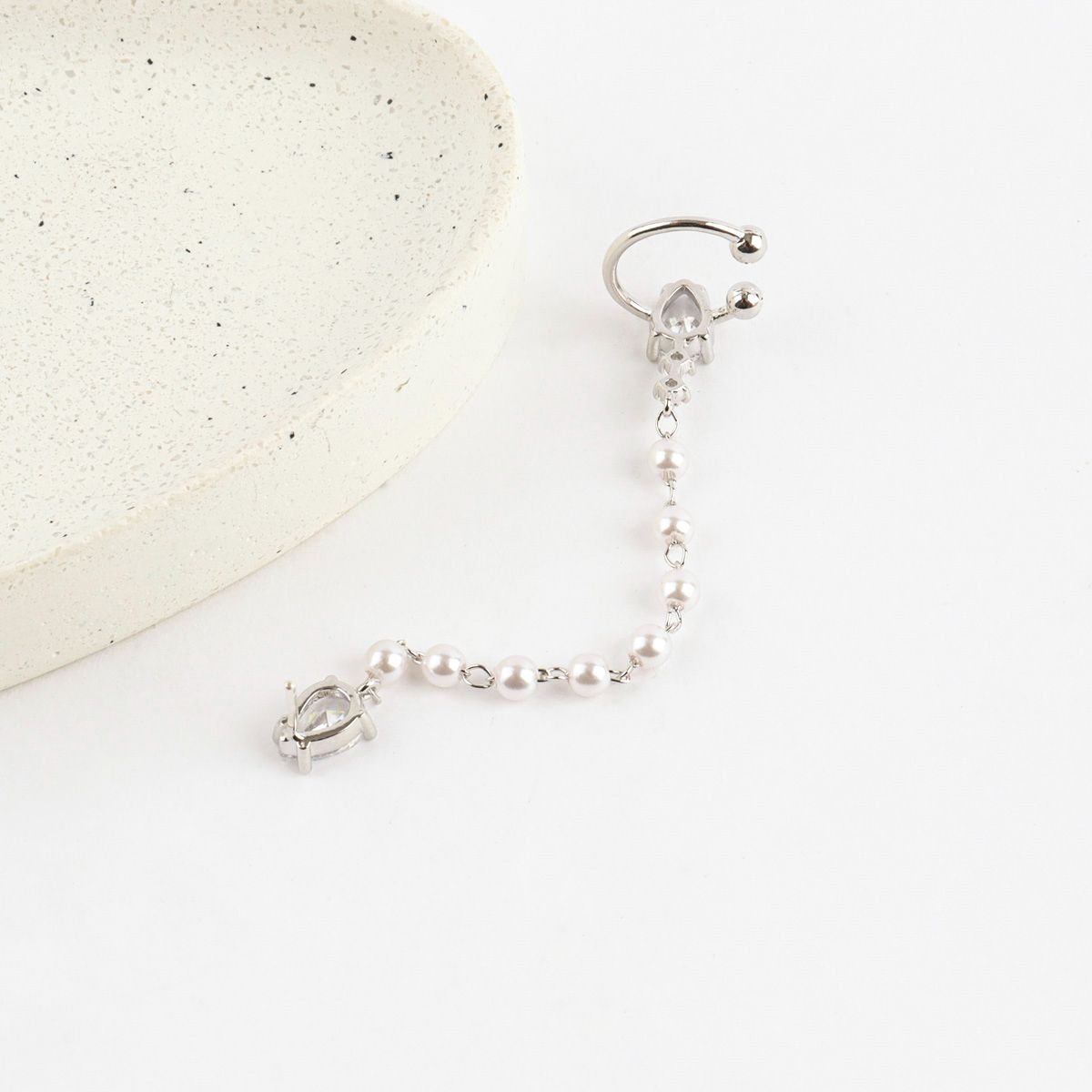 Silver earring with pearls on a white background