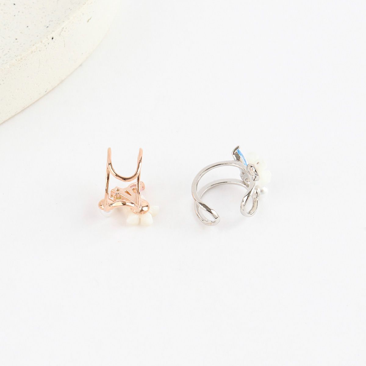 Two gold and silver hoop earrings on a light background