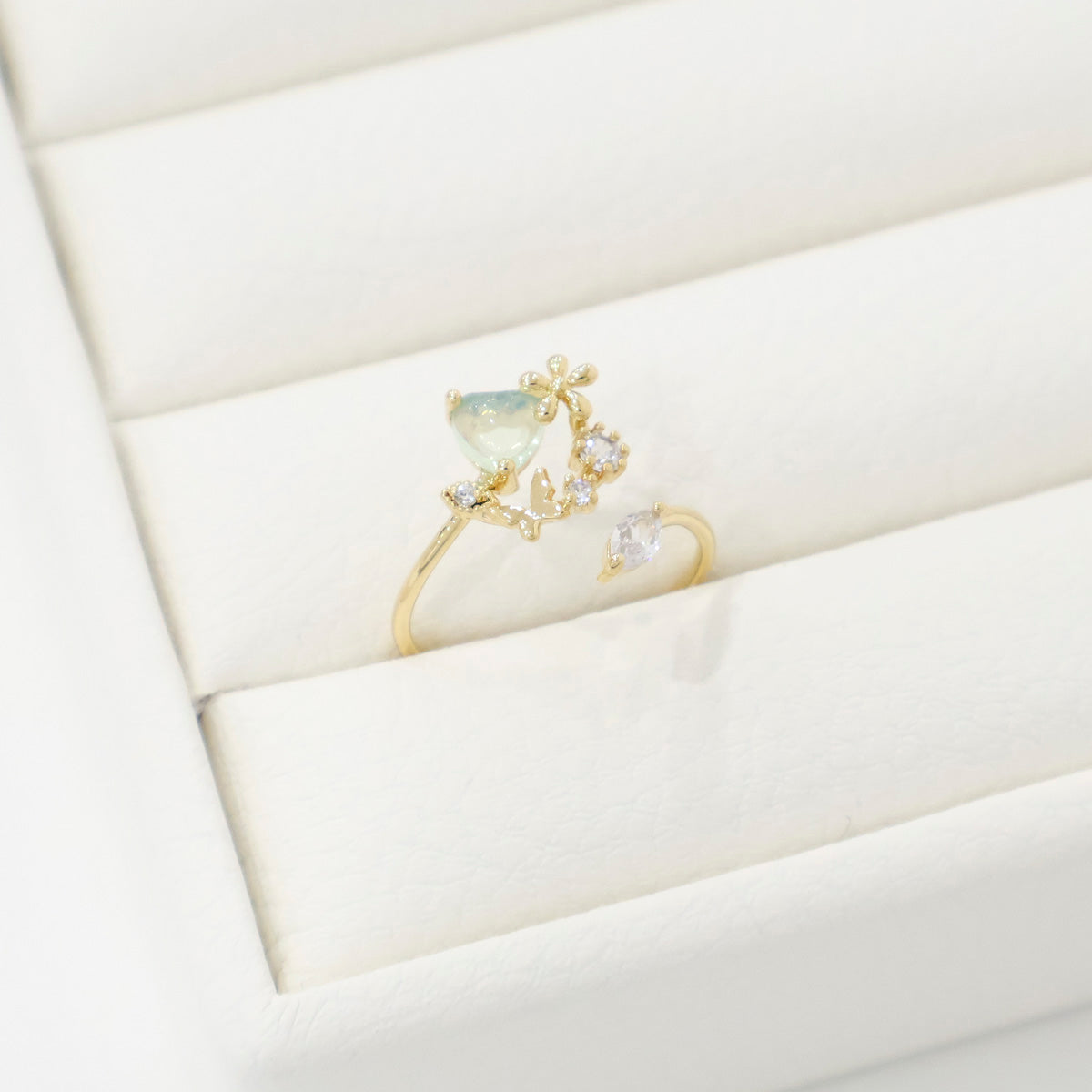 Gold ring with a central gemstone and smaller stones on a white fabric background