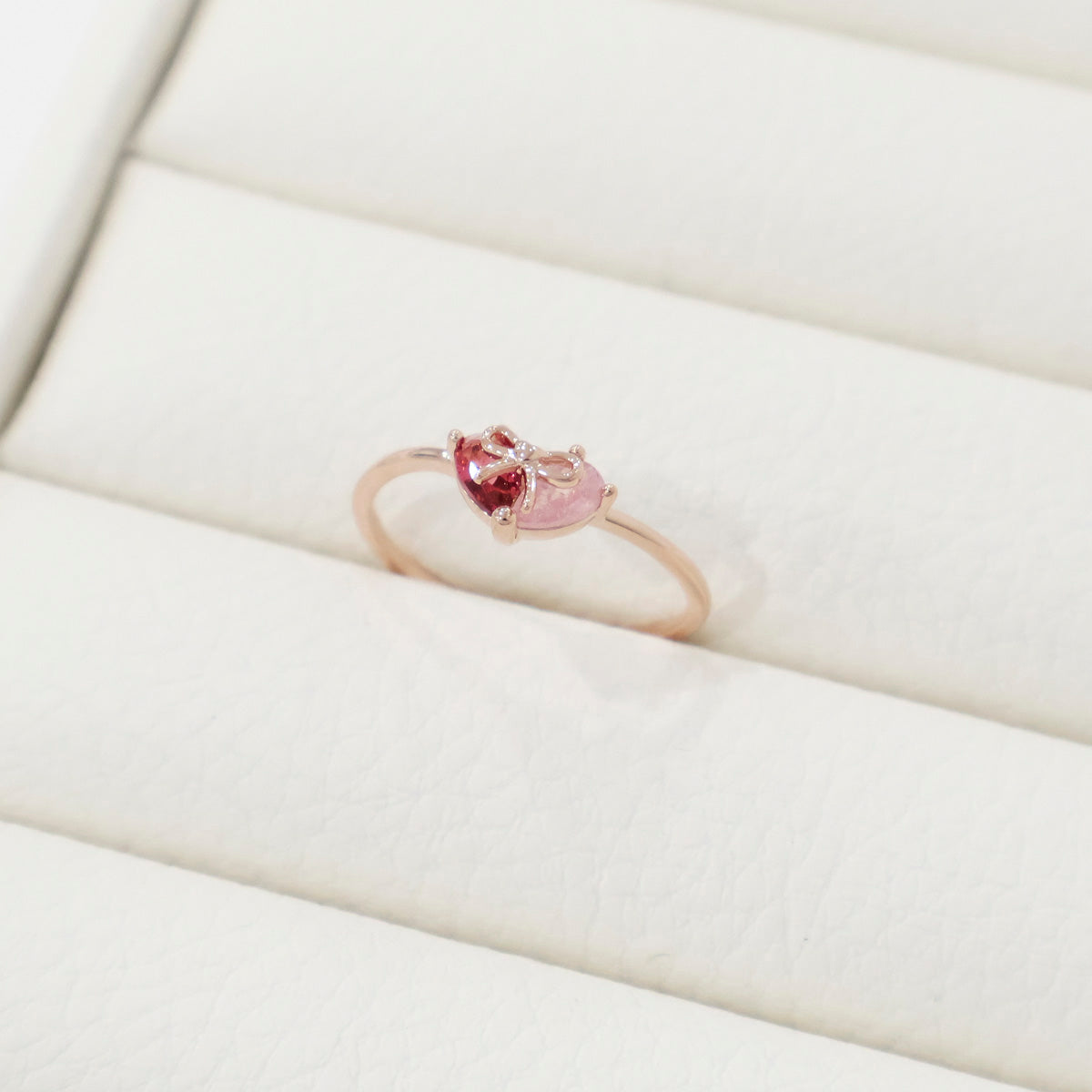 Gold ring with a pink gemstone on a white cushion