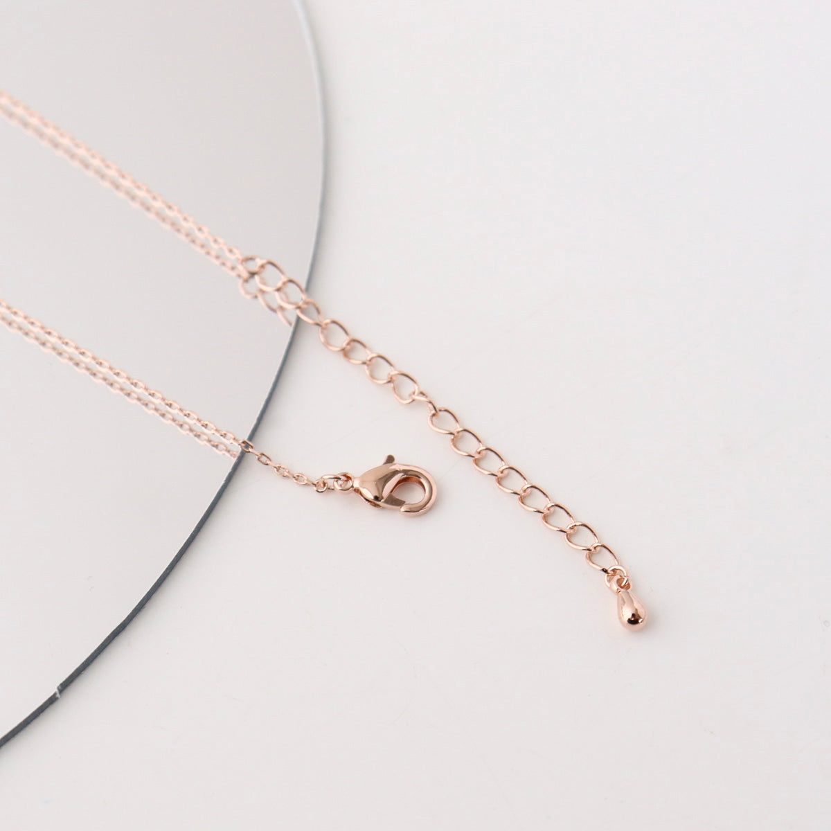 Rose gold chain necklace on a light gray background