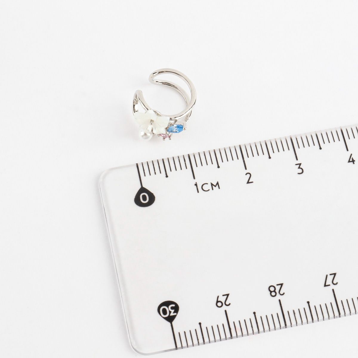 Ear cuff on a clear plastic ruler with measurement markings