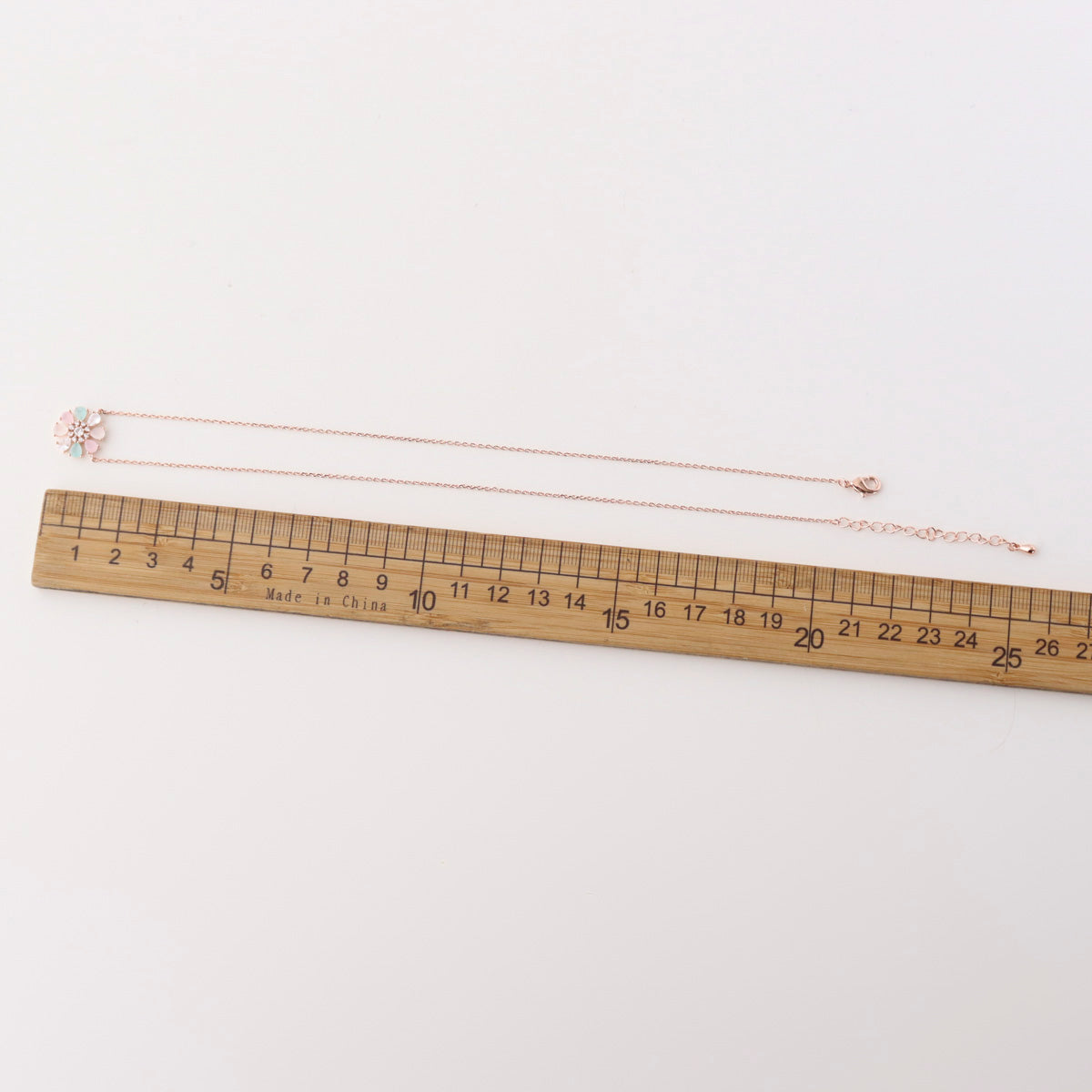 Necklace on a wooden ruler for size reference on a white background