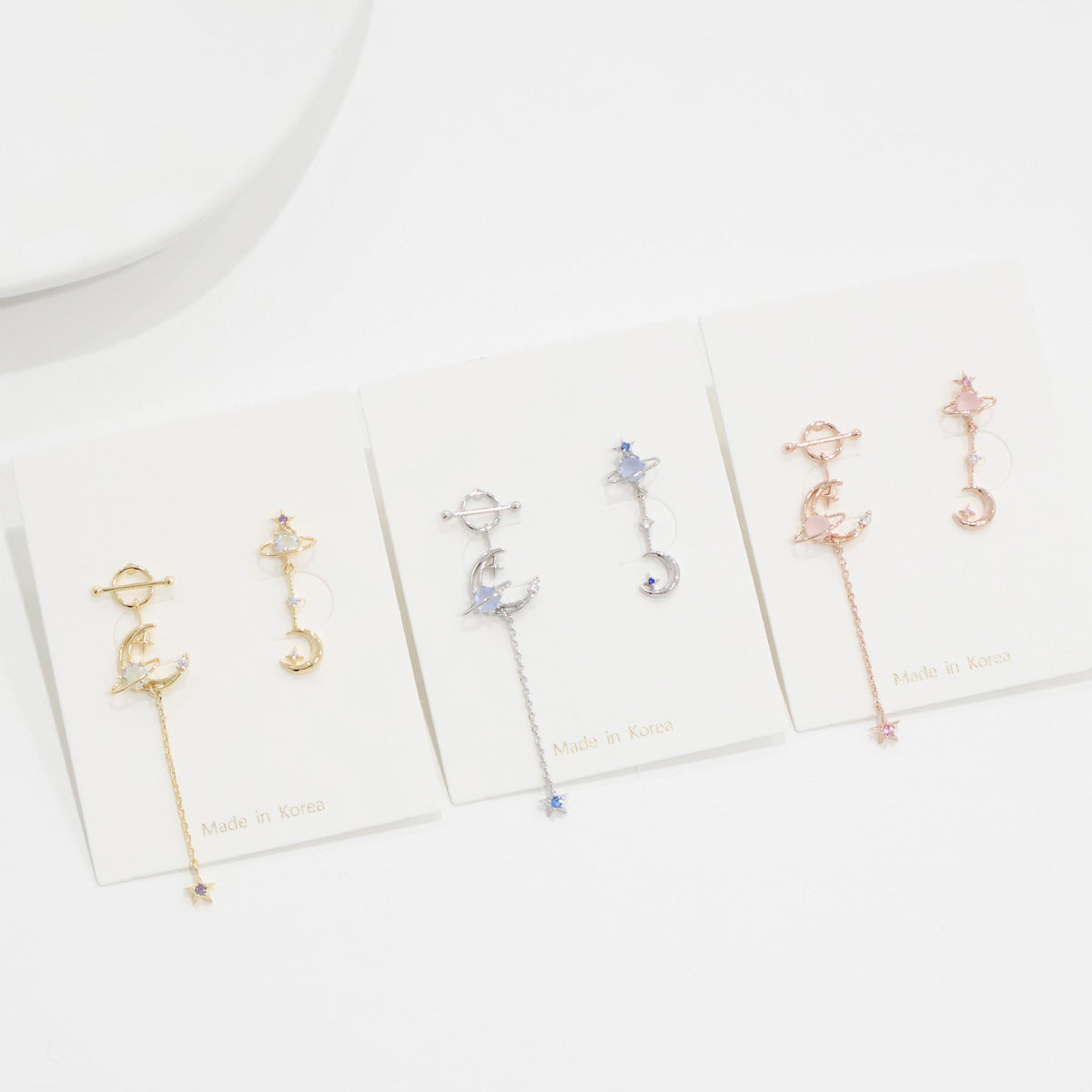 Set of earrings on branded cards against a white background