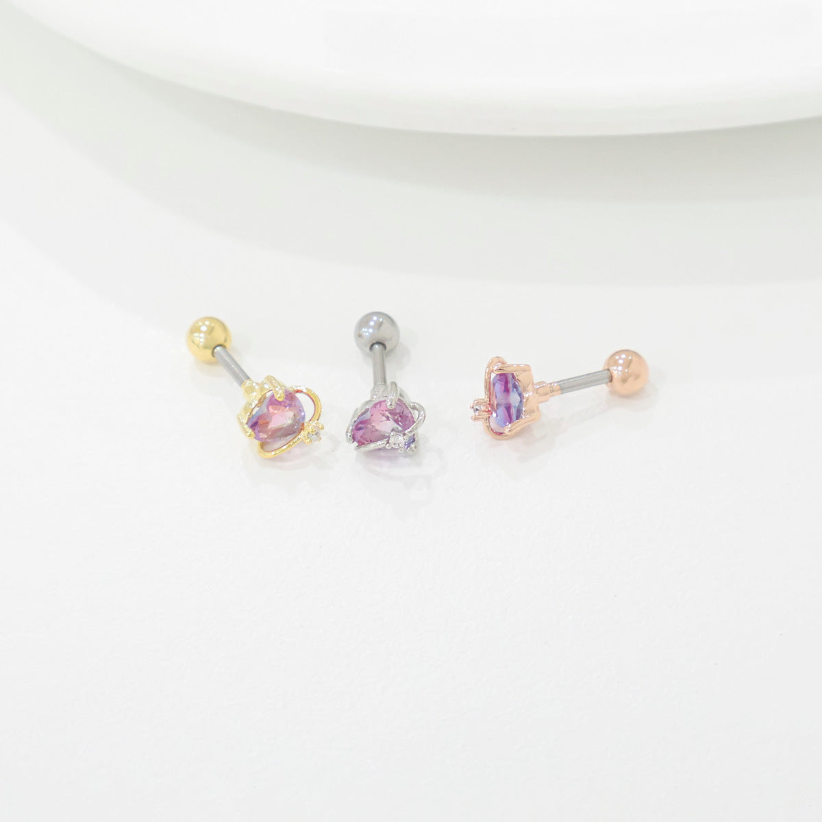 Three belly buttons with purple gemstones on a white background