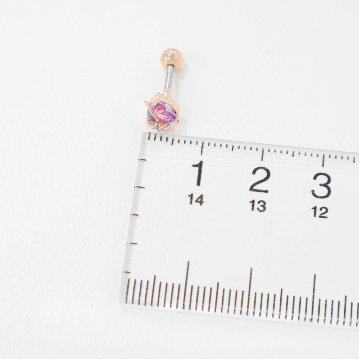 Belly button ring with gemstone on a ruler for size reference