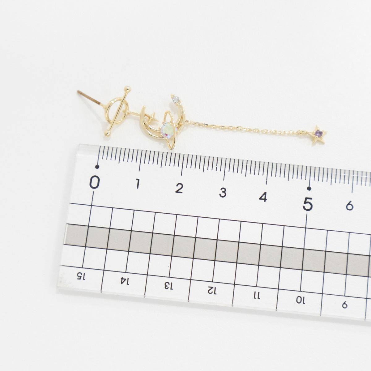 Gold bracelet with heart and key design on a ruler for scale