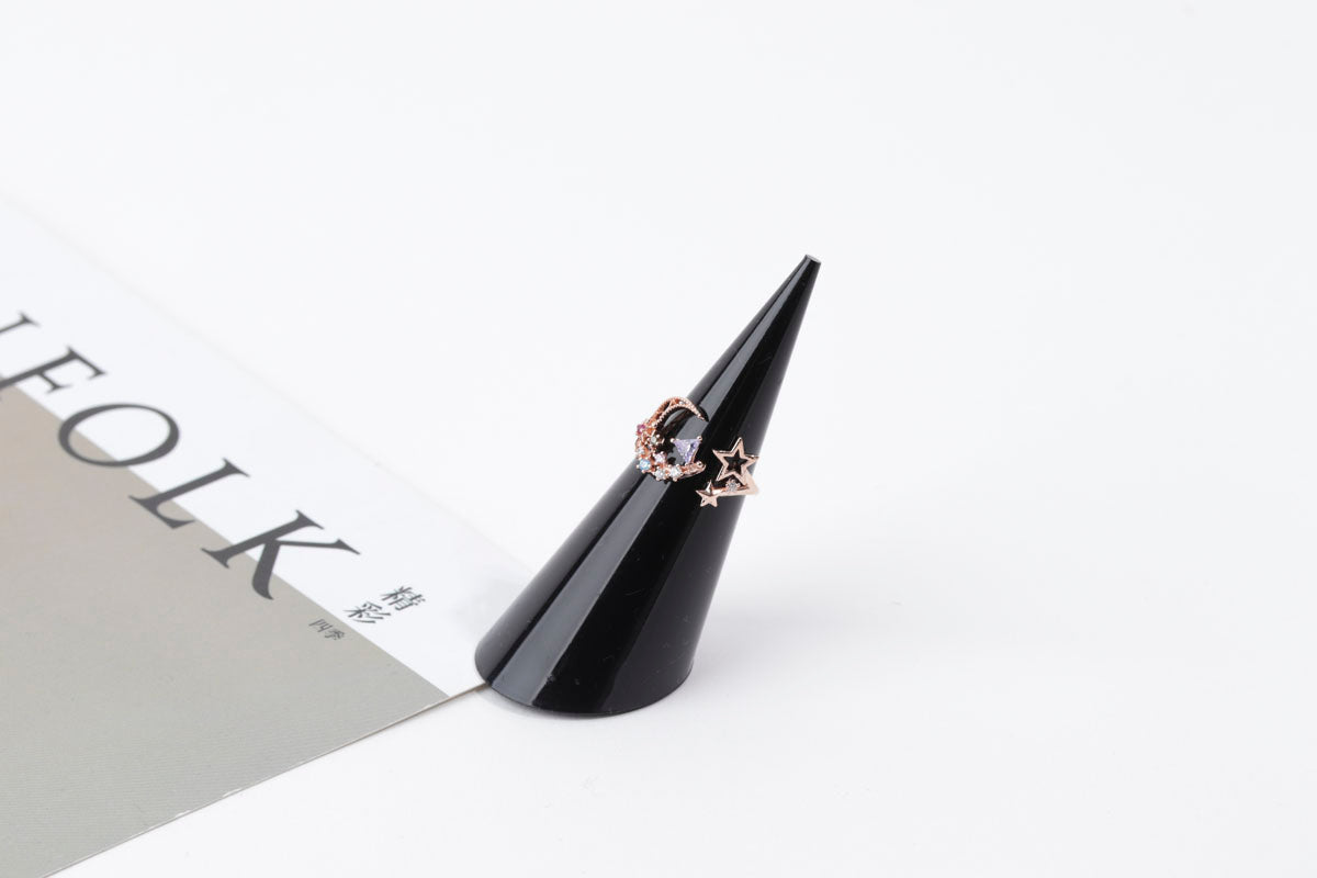Black cone-shaped jewelry stand with rings on a white background